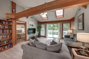 Relax in this airy living room with a comfortable sofa, coffee table, and bookshelf, perfect for unwinding.