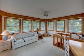 Relax in a spacious room with a high ceiling, large windows, and a comfortable sofa, perfect for families.