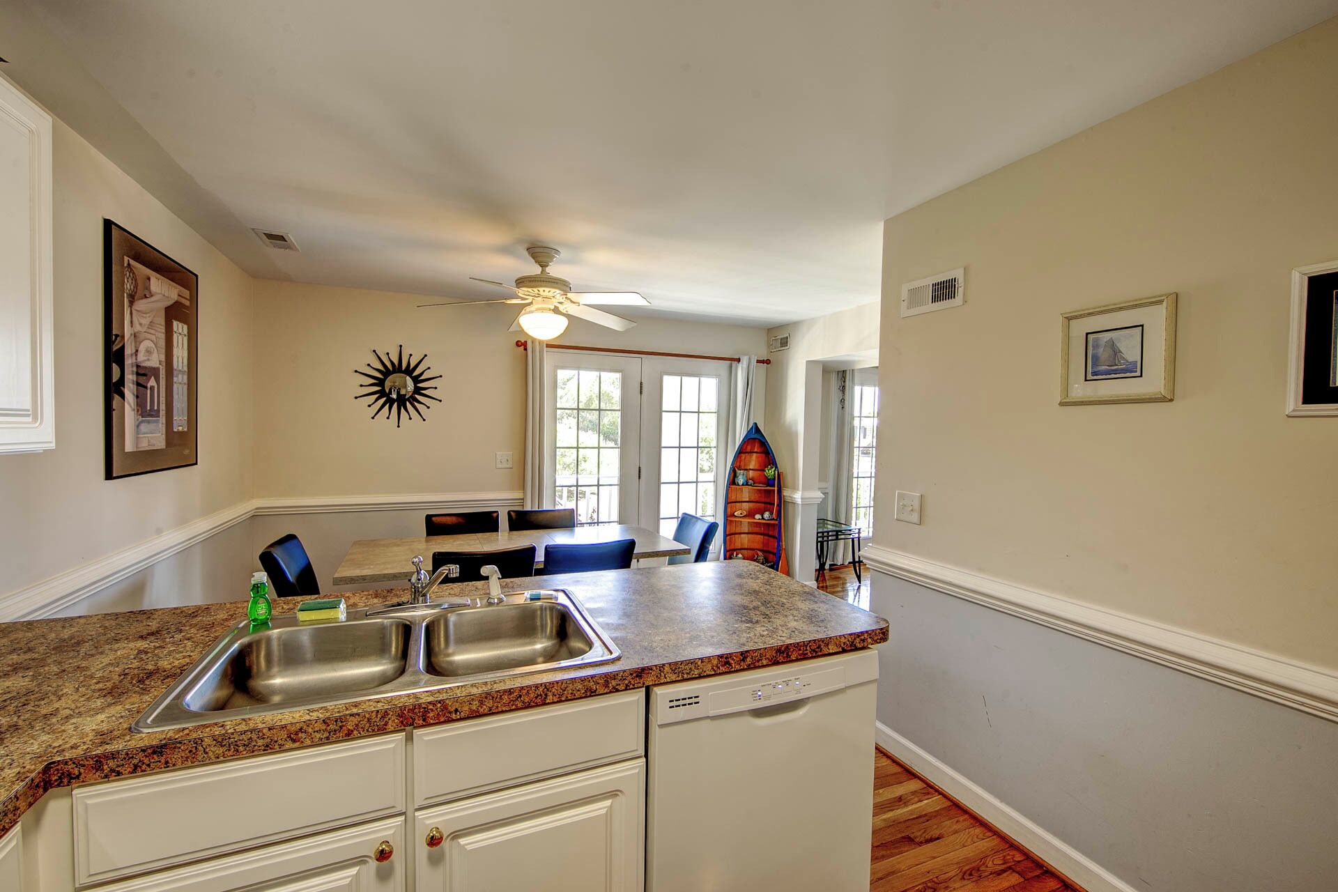A kitchen with a granite countertop, double sink, and white cabinetry.