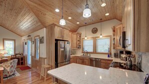 Une cuisine spacieuse, dotée de meubles en bois, d’un grand îlot central et d’appareils électroménagers modernes.