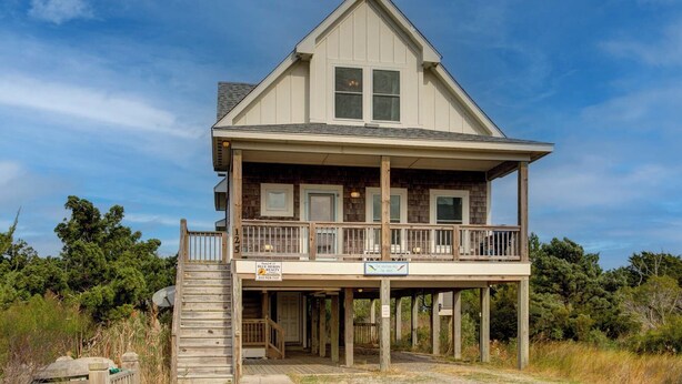 Une maison à deux étages dotée d’un balcon, d’une terrasse en bois et d’une pancarte indiquant qu’il s’agit d’un bien locatif.