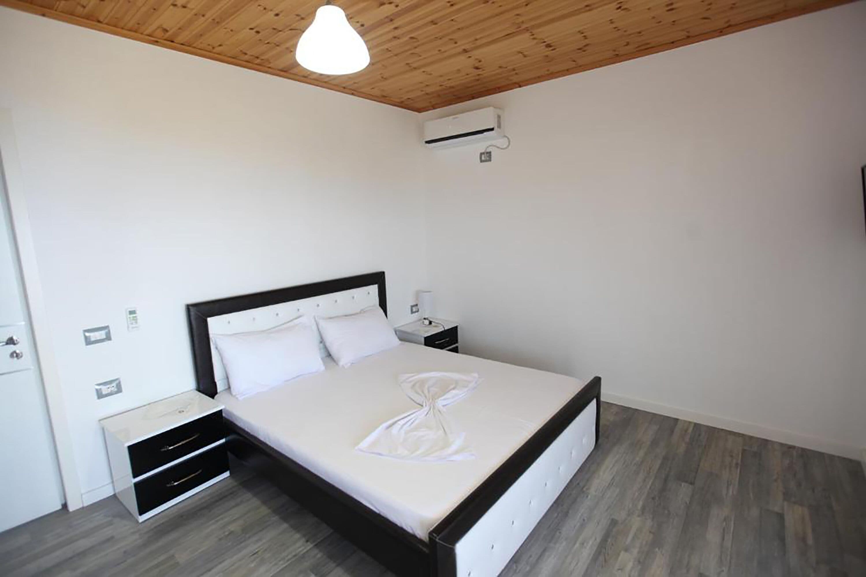 A neatly arranged bedroom with a bed, bedside tables, and a wardrobe.