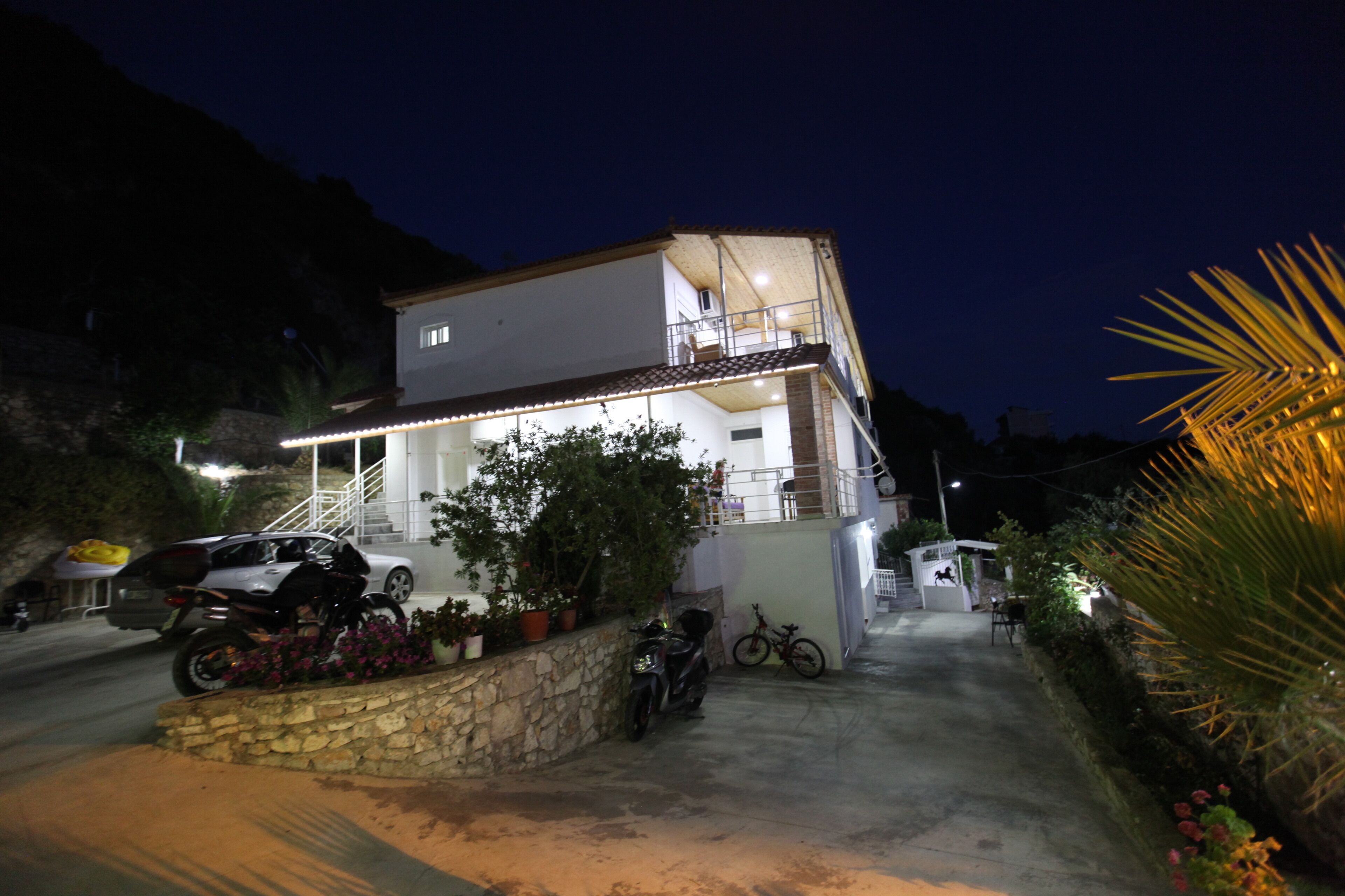 A two-story house with a balcony, a car, and a motorcycle parked in front.