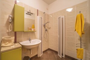 A bathroom with a sink, mirror, hairdryer, shower, and towel rack. - Holiday apartment with garden and air conditioning (Bibione)