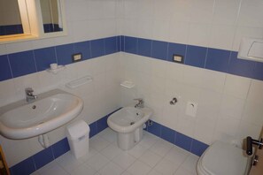 Une salle de bain équipée d’un lavabo, d’un bidet, de toilettes et d’un miroir.