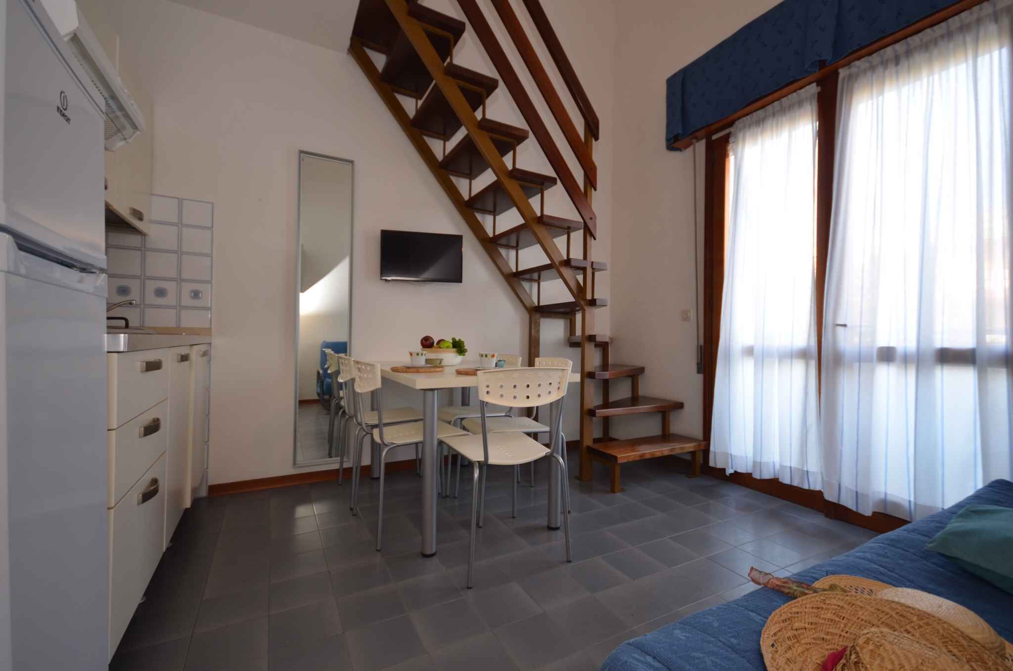 A compact living space with a kitchen, dining area, and a staircase.
