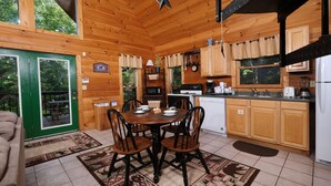 A wooden cabin with a dining table, chairs, and a kitchen area. - Hidden Ecstasy: Your Secret Mountain Bliss (Sevierville)