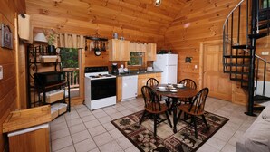 A wooden cabin interior with a kitchen, dining area, and a spiral staircase. - Hidden Ecstasy: Your Secret Mountain Bliss (Sevierville)