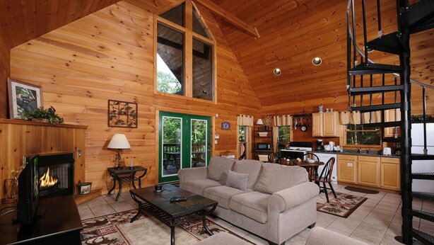 A cozy cabin interior with a fireplace, a sofa, a dining area, and a kitchen. - Hidden Ecstasy: Your Secret Mountain Bliss (Sevierville)