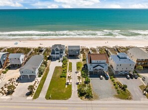 A beachfront property with multiple houses, a parking area, and a beach in the background.