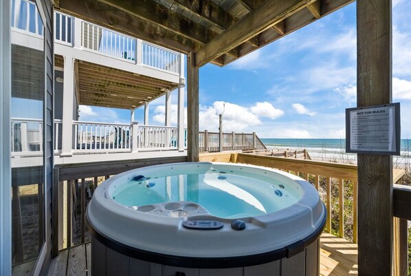 A hot tub on a wooden deck with a view of the beach.