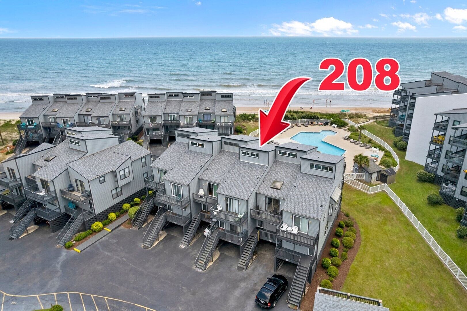 Un immeuble d’appartements moderne doté d’une piscine et offrant une vue sur la plage, portant le numéro 208.