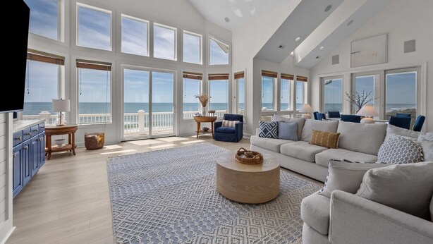 A spacious living room with large windows, a ceiling fan, and a view of the ocean. - New River Inlet Rd. 650 (North Topsail Beach)