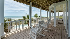 A wooden deck with white rocking chairs overlooking a beach and ocean. - New River Inlet Rd. 650 (North Topsail Beach)