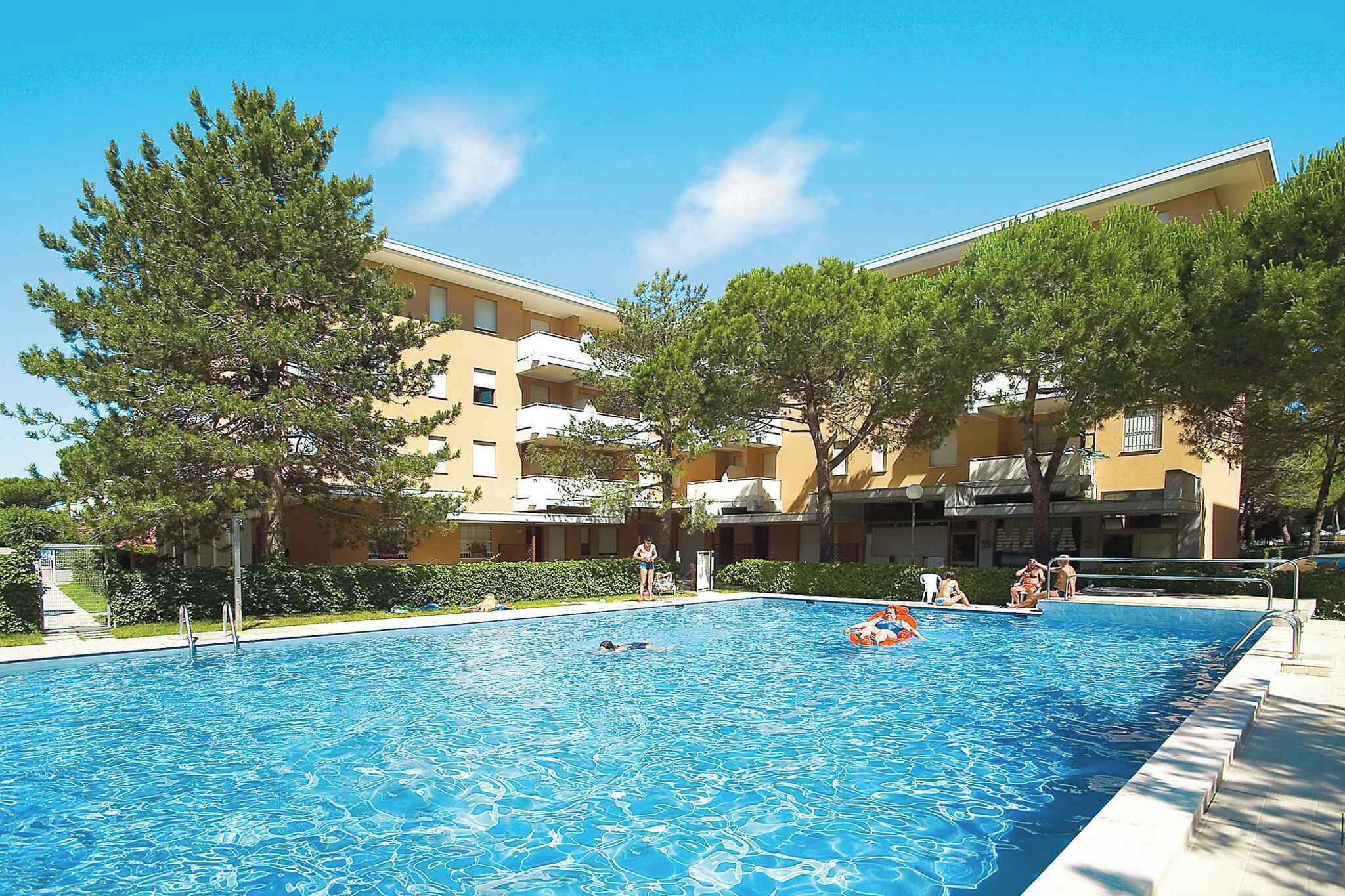 Una piscina rodeada de árboles y un edificio con balcones.