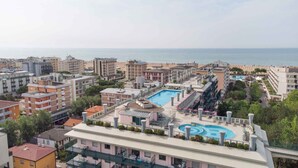 A hotel with a rooftop pool, multiple balconies, and a view of the sea.
