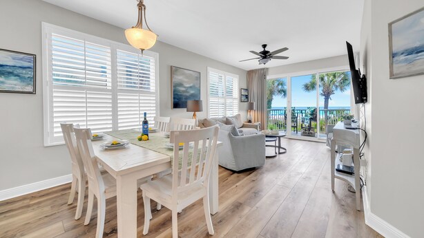 A dining area with a table and chairs, a ceiling fan, and a view of the outdoors.