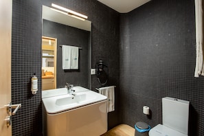 Une salle de bain moderne avec un grand lavabo, un miroir et des toilettes.