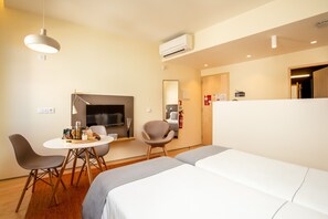 Une chambre d’hôtel comprenant un lit, une table à manger avec des chaises, une télévision et une petite kitchenette.