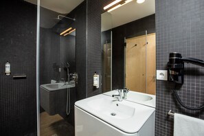 A modern bathroom with a large sink, mirror, and shower area.