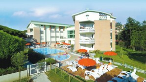 Un hotel con varias piscinas, sillas de descanso y sombrillas.