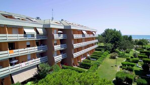 Un hotel de varios pisos con balcones, un jardín y vistas al mar.