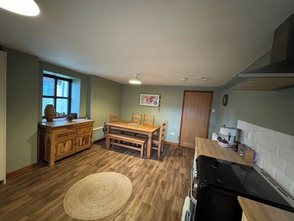 A compact kitchen with wooden cabinets, a dining table, and a black stove.