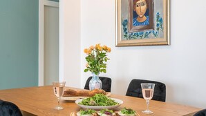 A dining table with a loaf of bread, a bowl of salad, and a plate of sliced bread with greens. There are two glasses of water and a glass of wine on the table. - Panoramic Sea Views Coastal Escape by Sea N' Rent (Nahariya)
