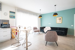 Una cocina moderna con microondas, estufa y comedor con sillas y mesa.