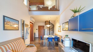 Un interior moderno con comedor, cocina y sala de estar con sofá y televisor.
