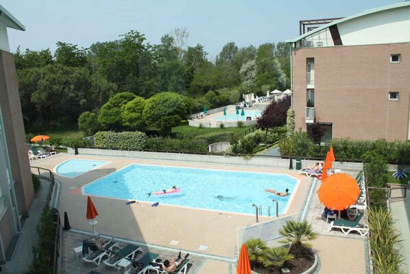 A rooftop swimming pool with two separate sections, surrounded by lounge chairs and umbrellas.
