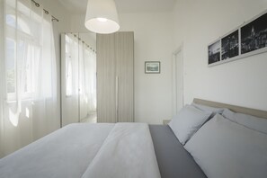 Ein modernes Schlafzimmer mit einem großen Bett, einem Nachttisch, einer Hängeleuchte und einem Stadtbild an der Wand.