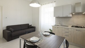 Una cucina moderna con zona pranzo, divano e lampada a sospensione.