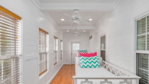 A narrow hallway with white walls, wooden floors, and a white bench with pillows. - Contemporary Beach Home Near Back River for the Whole Crew by Tybee Cottages (Tybee Island)