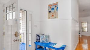 A room with a blue bench, a poster on the wall, and a door leading to an outdoor area. - Contemporary Beach Home Near Back River for the Whole Crew by Tybee Cottages (Tybee Island)