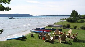 Un entorno junto al lago con canoas, sillas y una mesa sobre el césped cerca del agua.