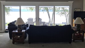 A living room with a dark blue sofa, two lamps with stone bases, and a view of a body of water through large windows.