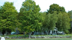 A lakeside property with a dock, surrounded by lush trees and a stone-lined walkway.