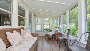 A sunroom with a wicker sofa, a chair, and a small table.