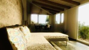 Una habitación acogedora con sofá, una mesa de comedor, ventanas amplias y vistas a zonas verdes.