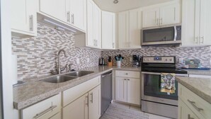A kitchen with white cabinets, a microwave, an oven, and a sink. - Turtle Bay Heliconia. (Kahuku)