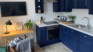 A modern kitchen with dark blue cabinets, a white countertop, a built-in oven, a toaster, and a sink. - Beautiful 1-bed Apartment in Kirkby Lonsdale (Carnforth)