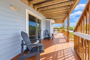 A covered deck with two Adirondack chairs, a sliding glass door, and a wooden railing. - Time to Chill - Corolla, Whalehead, Ocean View, 480 Yds to Beach, Pool, Flex Stays (Corolla)
