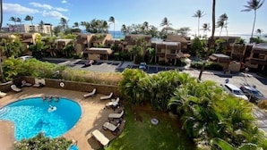 A resort with a swimming pool, lounge chairs, and palm trees. - Kamaole Beach Royale 301 ~ 3 bedroom (Kihei)