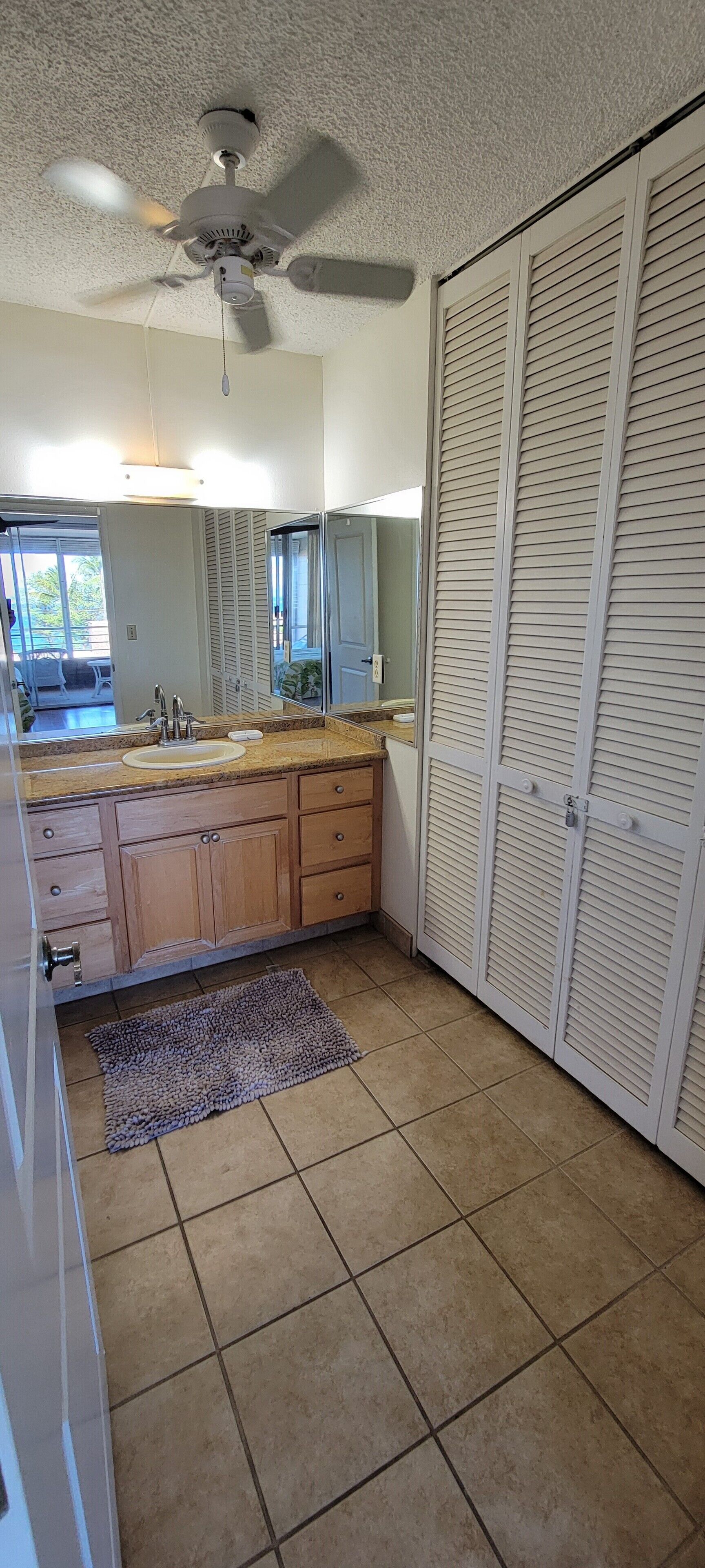 A bathroom with a sink, mirror, and a ceiling fan.