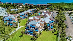 Vista aerea di un resort con diversi edifici, un'area parcheggio e vista sull'oceano.