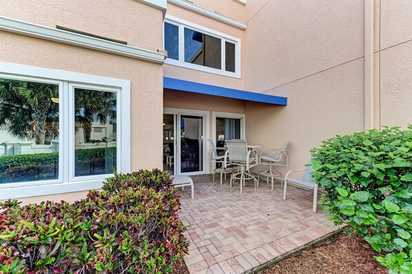 A patio area with a table and chairs, a bench, and a small garden. - Unit #101 Sand Cay, Gulf View, Steps to Beach, Recently Remodeled (Longboat Key)
