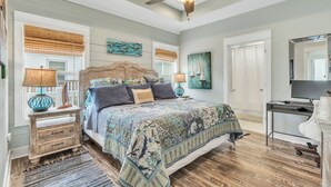 Una camera da letto con un letto in legno, due comodini con lampade, un ventilatore a soffitto e opere d'arte alle pareti.