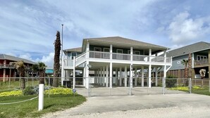 Un edifici de dues plantes amb un balcó, envoltat per una tanca i palmeres.