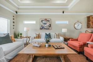 A living room with a white sofa, a wooden coffee table, a red armchair, and a large abstract painting on the wall. - ALL DECKED OUT - 2 Bedroom, 2 Bath, Sleeps 6 - Beach Front! (Crystal Beach)